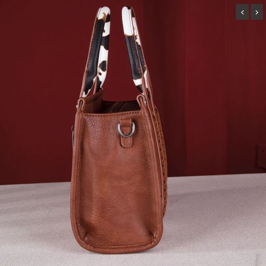 Side view of the Wrangler Cow Print Concealed Carry Tote/Crossbody - Brown with cow print handles and durable simulated leather.