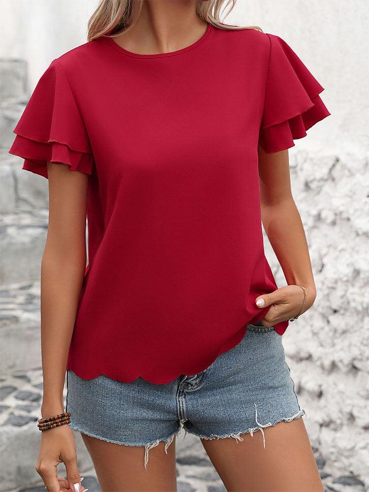 Woman wearing Lotus Blossom Ruffle Top - Stylish Red Double-layer Lotus Leaf Sleeve Blouse with scalloped waist and denim shorts.