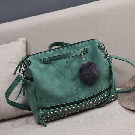 Rustic Charm Leather Shoulder Bag – Stylish Cowgirl Handbag in green with rivet details, displayed on a sofa.