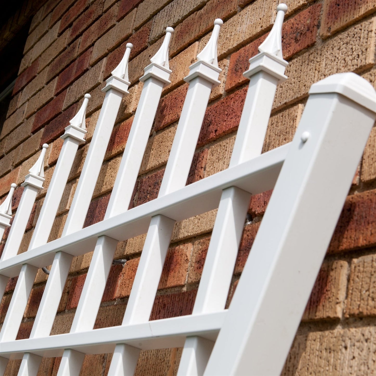 7.75 Ft Fan Shaped Garden Trellis with Pointed Finals in White Vinyl against brick wall