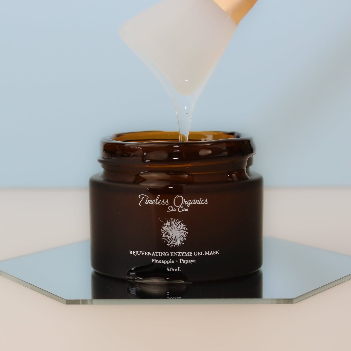 Rejuvenating Enzyme Gel Mask with fruit enzymes in a 50mL brown jar on a reflective surface.