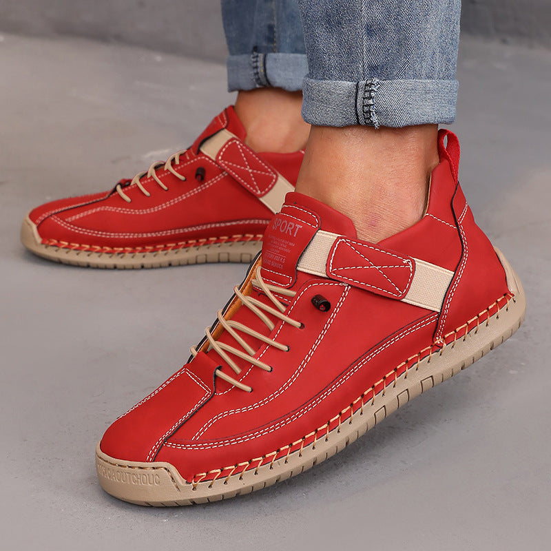 Men's stylish red leather sneakers with beige accents, cropped jeans, gray floor background.