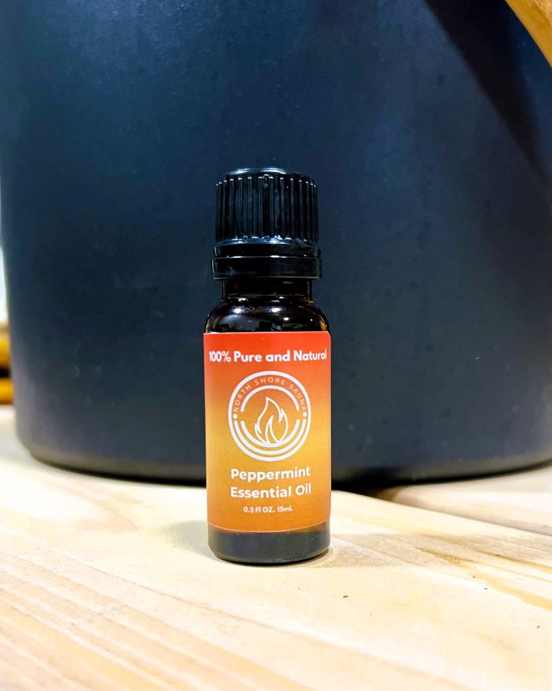 Peppermint Essential Oil 0.5oz bottle on wooden surface; 100% pure and natural.