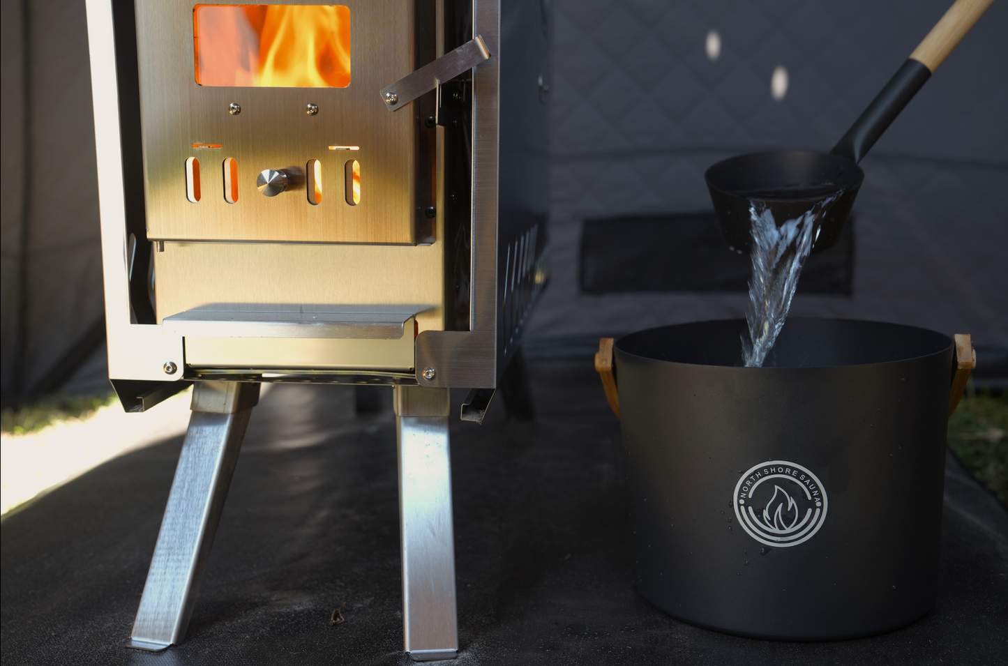 5L Black Aluminum Sauna Bucket and Ladle Set with Elegant Bamboo Handles next to a sauna heater with water being poured.