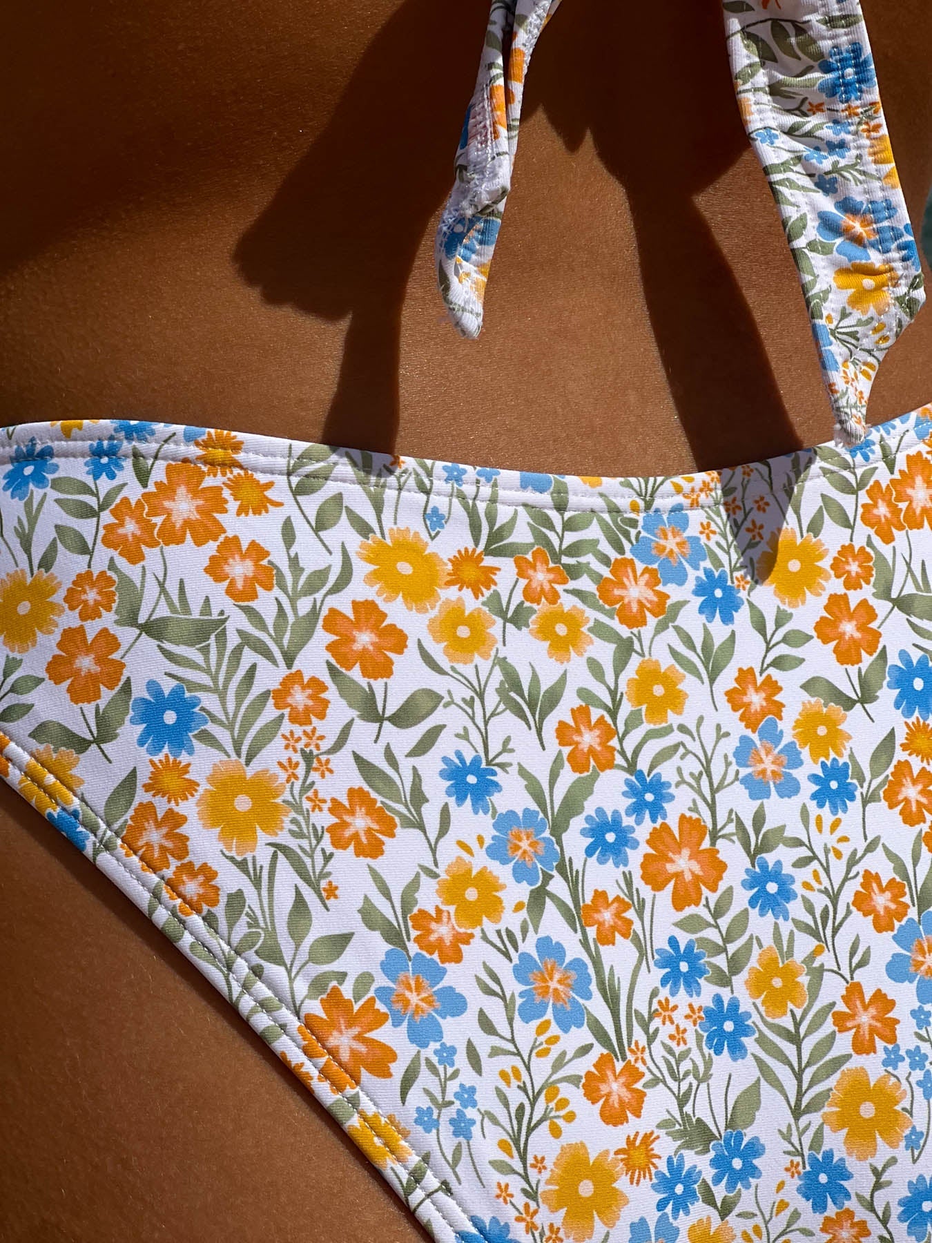 Close-up of floral patterned sky bottom - saint tropez swimwear with vibrant orange, yellow, and blue flowers.