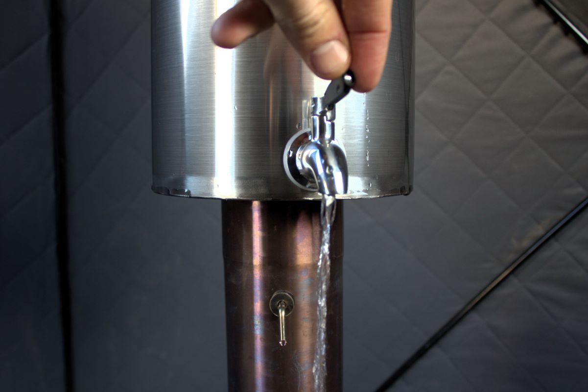 Sauna Tent Water Heater attached to a chimney pipe with a hand operating water tap.