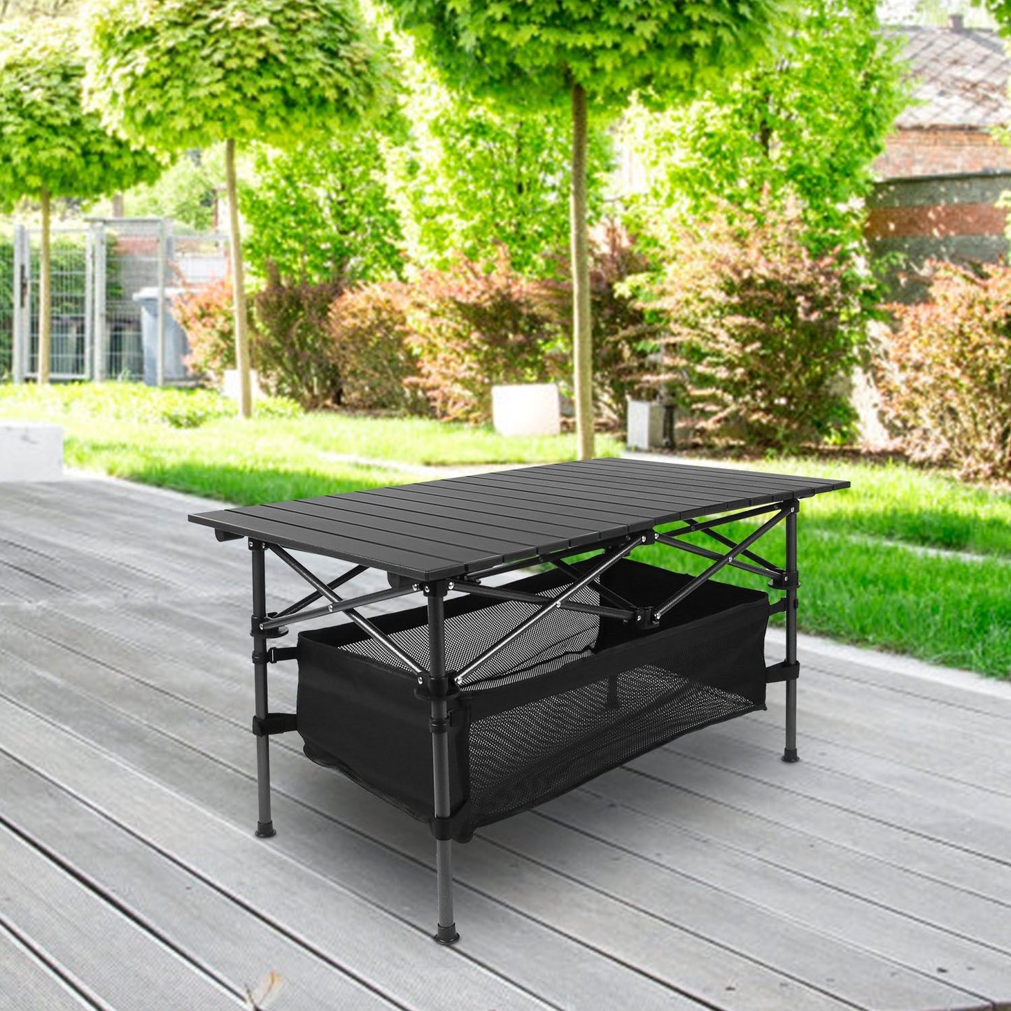 Folding camping table with aluminum roll-up design and storage mesh, ideal for picnics, BBQs, and outdoor parties, set on patio.