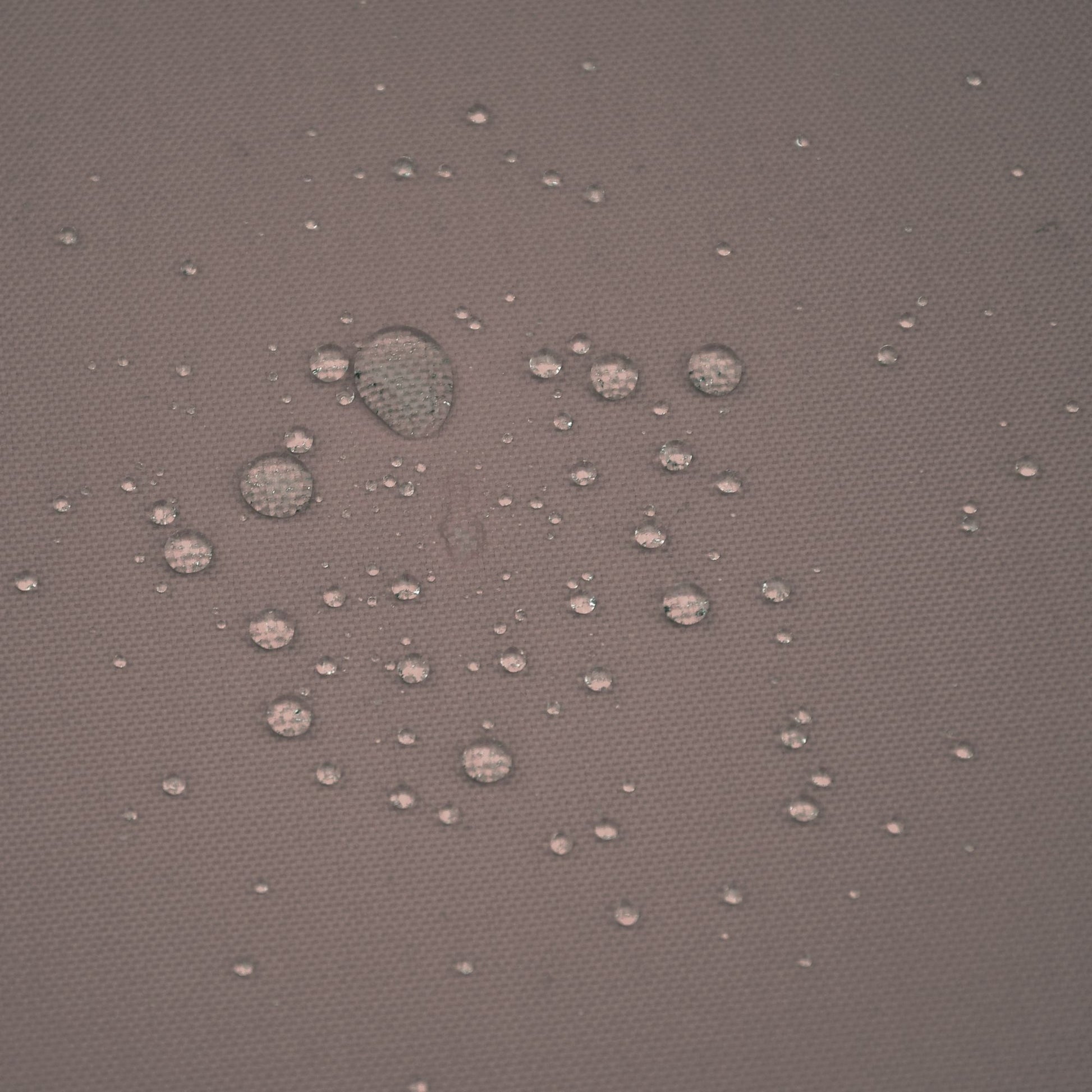 Close-up of water-resistant fabric on Adjustable Wicker Recliner Chair, showing droplets on the surface.