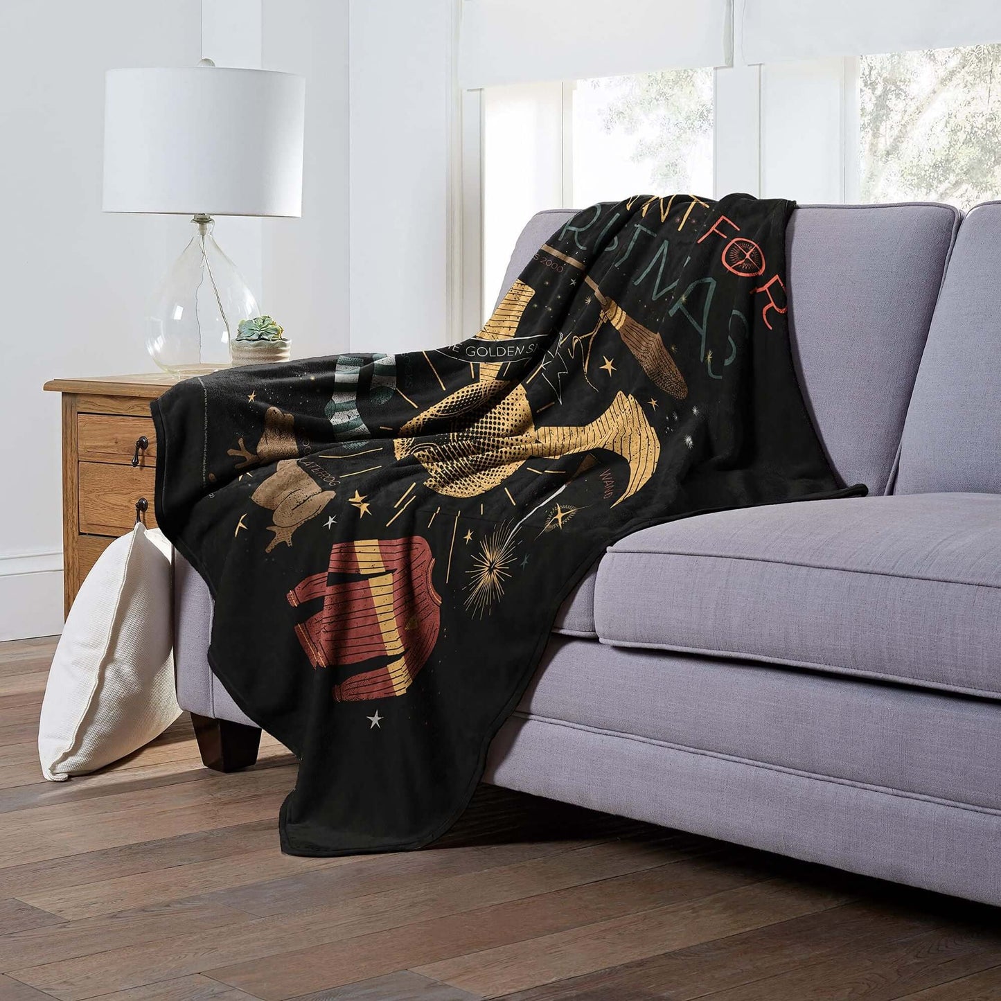 Harry Potter Silk Touch Throw Blanket displayed on sofa, showcasing All I Want For Christmas design, ideal for cozy evenings.