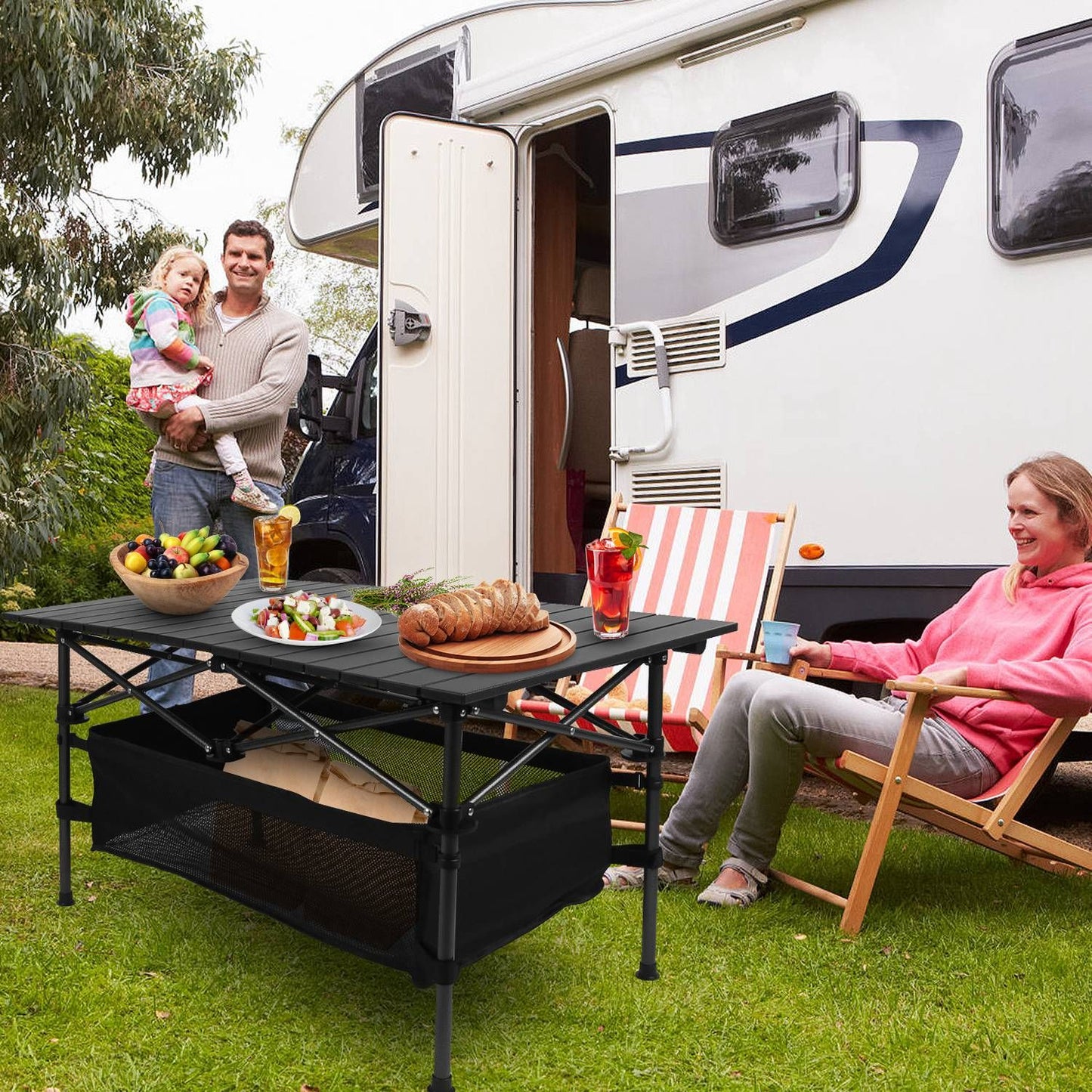 Portable lightweight aluminum folding camping table with roll-up design, storage mesh basket, set up for picnic outside an RV.