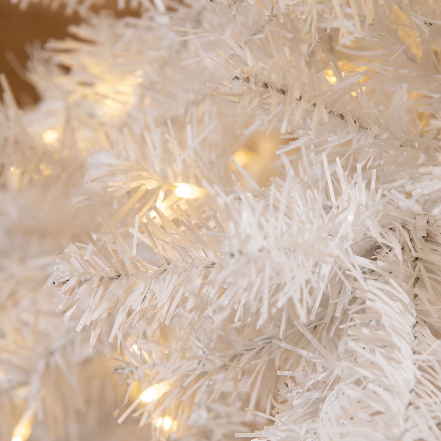 Close-up of White Christmas Tree with warm white LED lights on branches.