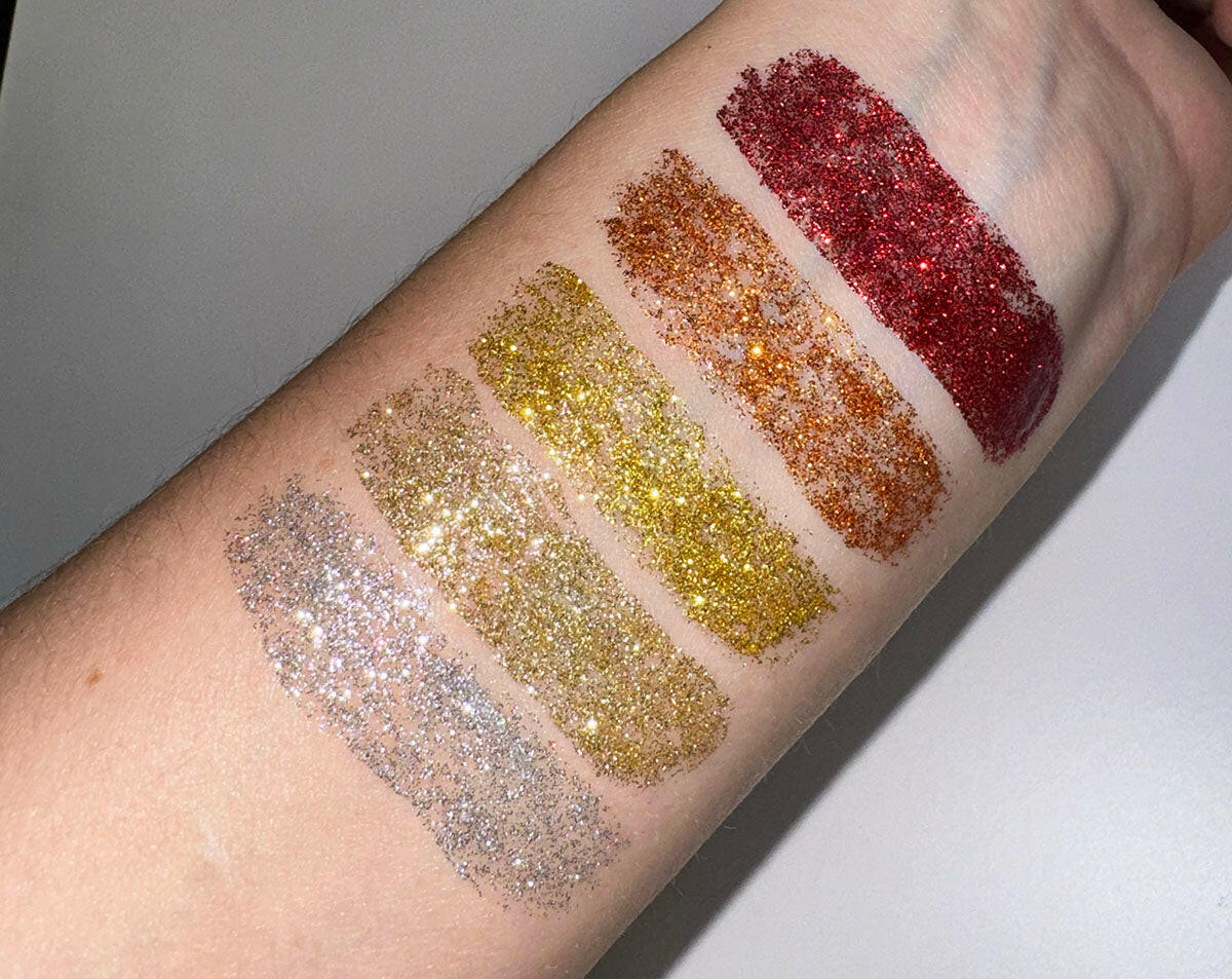 Mystic - Flicker Glitter Eyeliner swatches on arm showcasing copper, gold, silver, and red shades with sparkling texture.