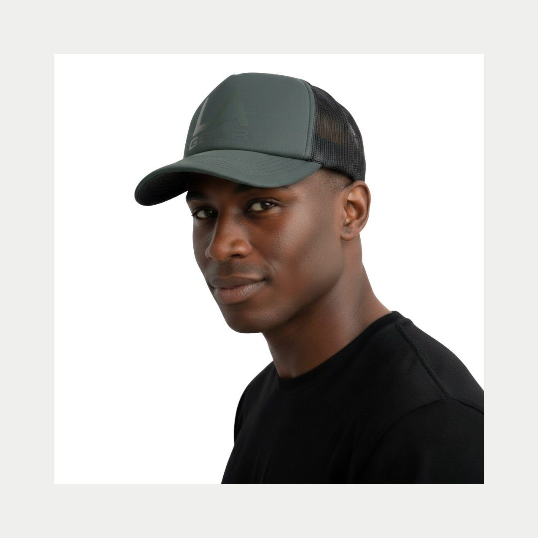 Young man wearing LA Gear Foam Trucker Hat | Sage, featuring a foam front with vinyl logo and mesh back for breathability.
