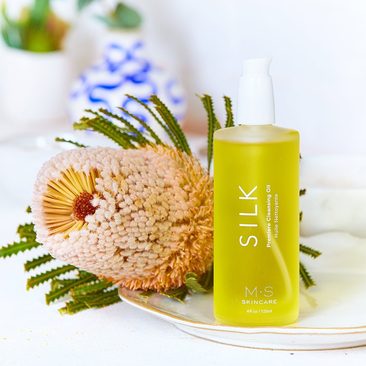 SILK Ayurvedic cleansing oil with nutritive oils and Frankincense for a refreshed complexion, shown with natural flowers.