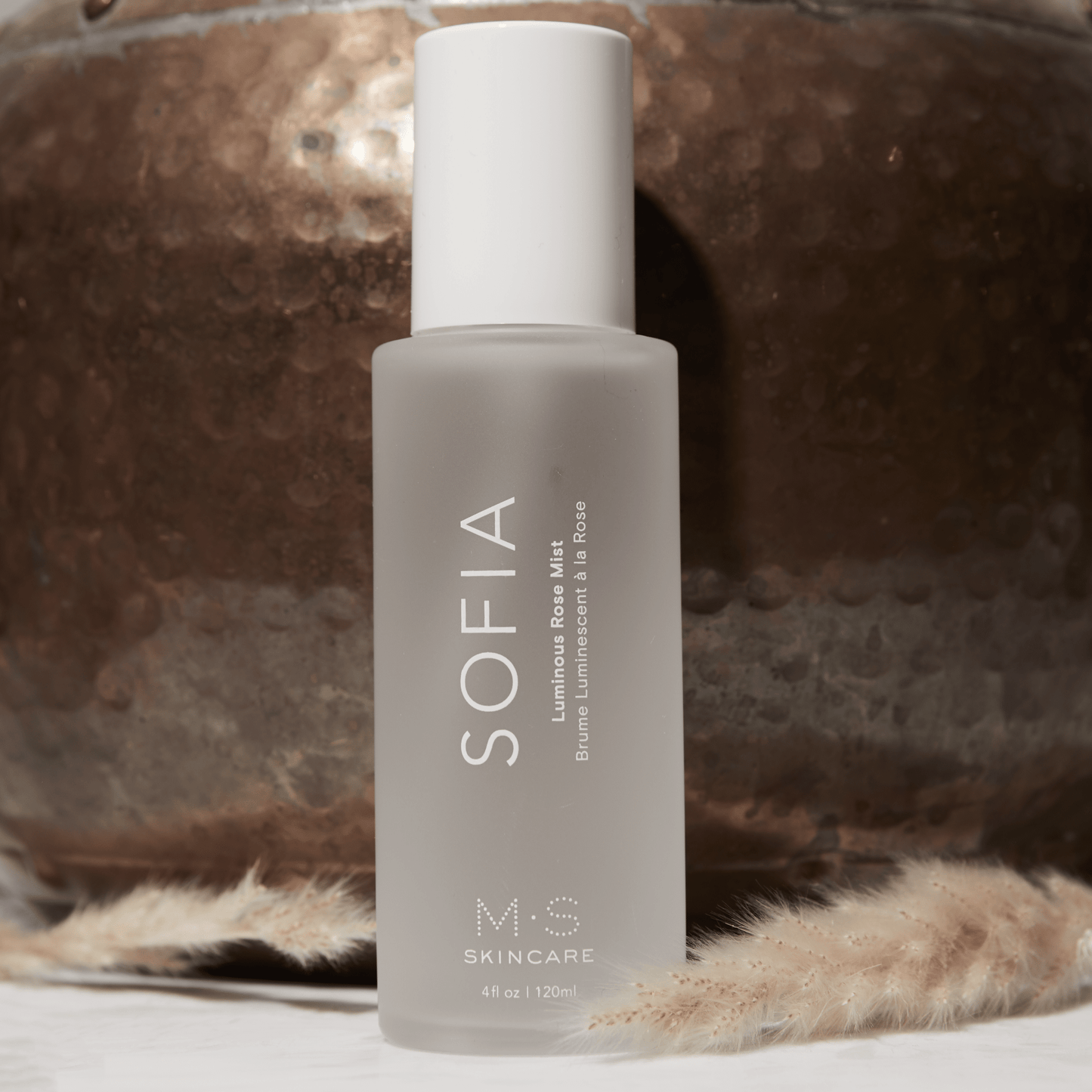 SOFIA Luminous Rose Mist bottle on rustic background, 4 fl oz / 120 ml, featuring antioxidants for radiant skin.
