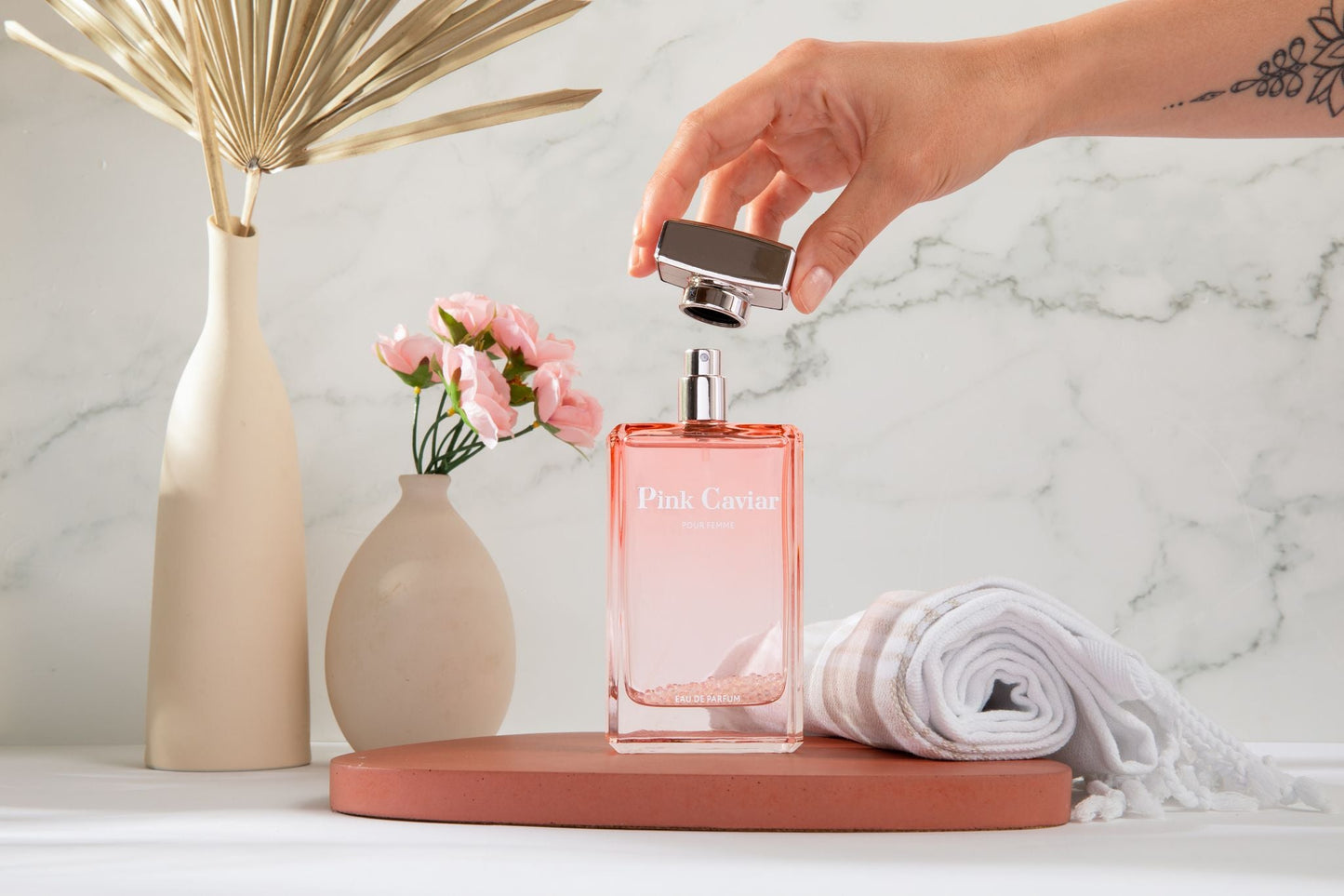 Syren - Pink Caviar perfume bottle on table with flowers and decorative vase