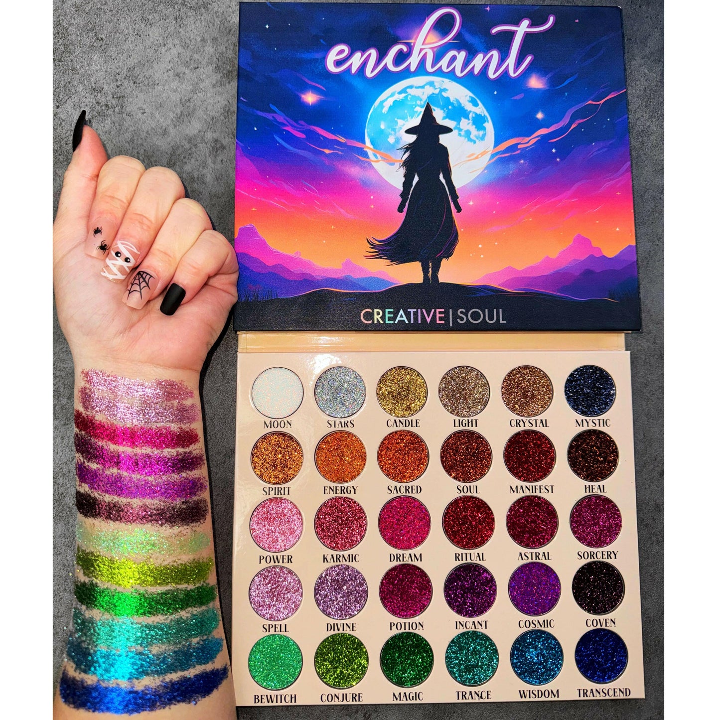 Enchant Pressed Glitter Eyeshadow Palette with vibrant swatches on arm showcasing iridescent to golds, purples, and blues shades.