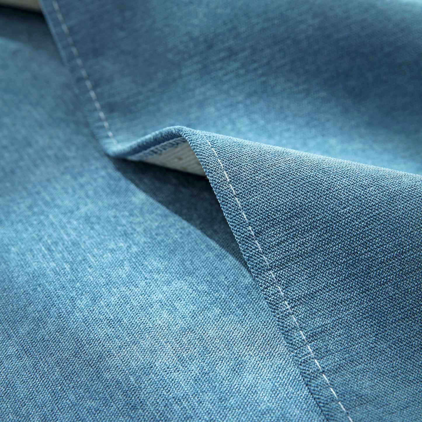 Close-up of blue fabric texture, showcasing stitching detail on a sofa cover