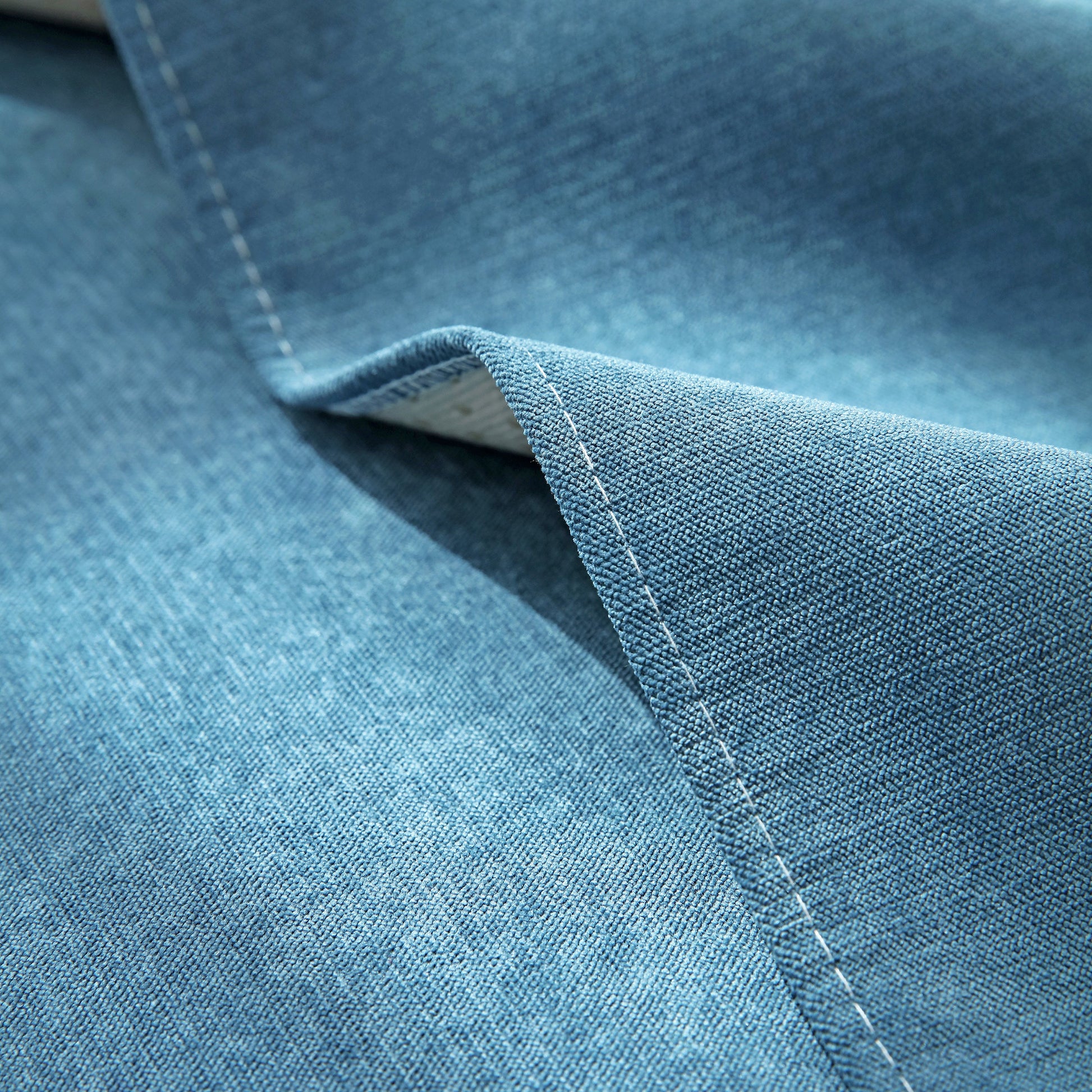 Close-up of blue fabric texture, showcasing stitching detail on a sofa cover