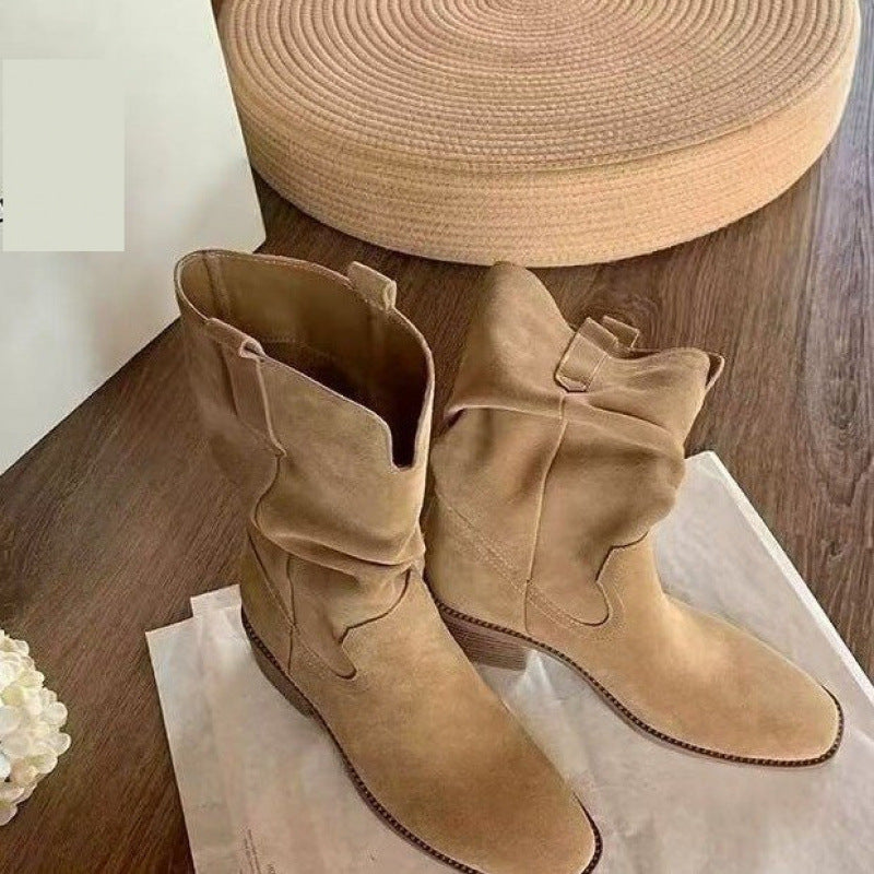 Autumn Western Pleated Short Cowhide Leather Boots for Women on wooden floor with beige decorative items.