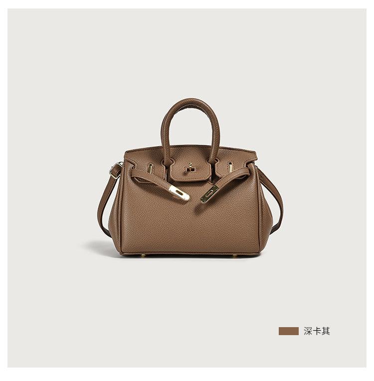 Brown leather handbag with handles and shoulder strap on a white background.