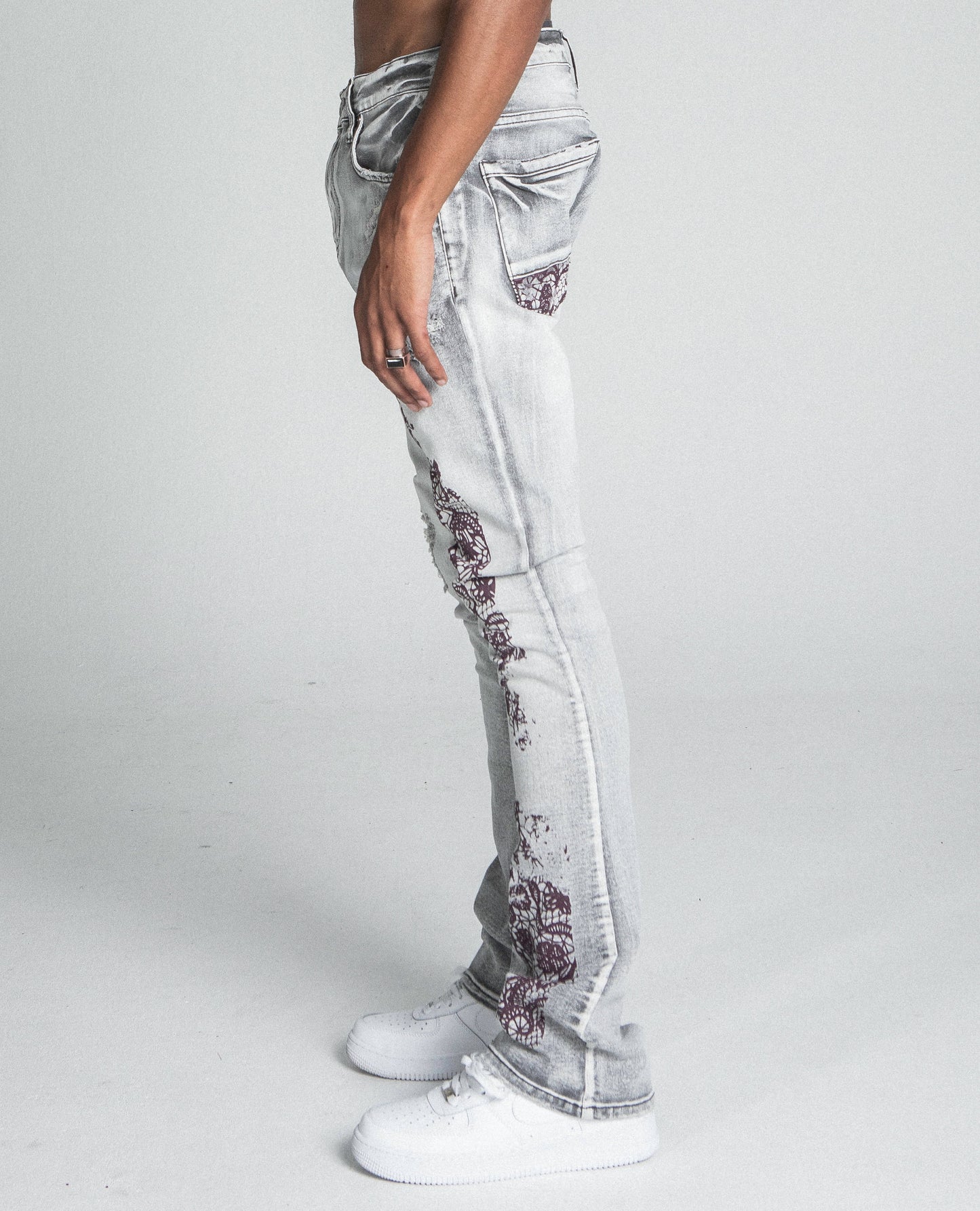 Model wearing AJ27SK LACE FADED WASH STACKED JEANS showcasing lace design and mid-rise fit with white sneakers.