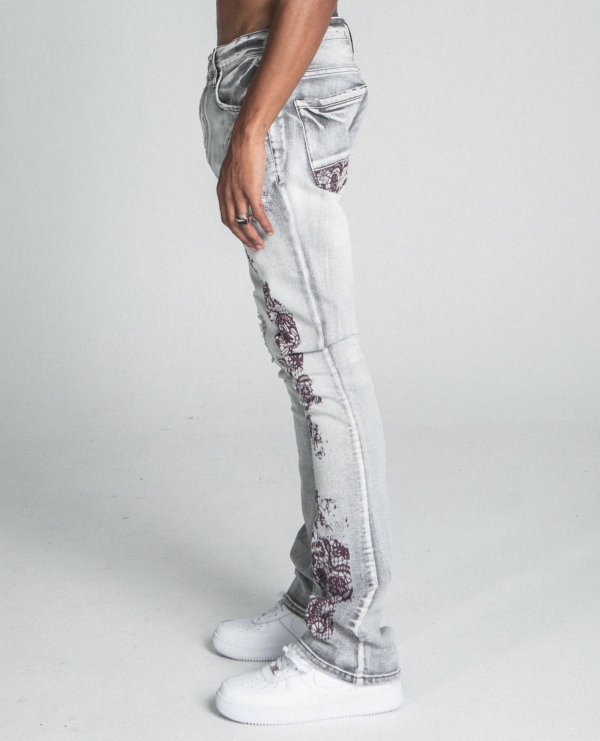 Model wearing AJ27SK LACE FADED WASH STACKED JEANS showcasing lace design and mid-rise fit with white sneakers.