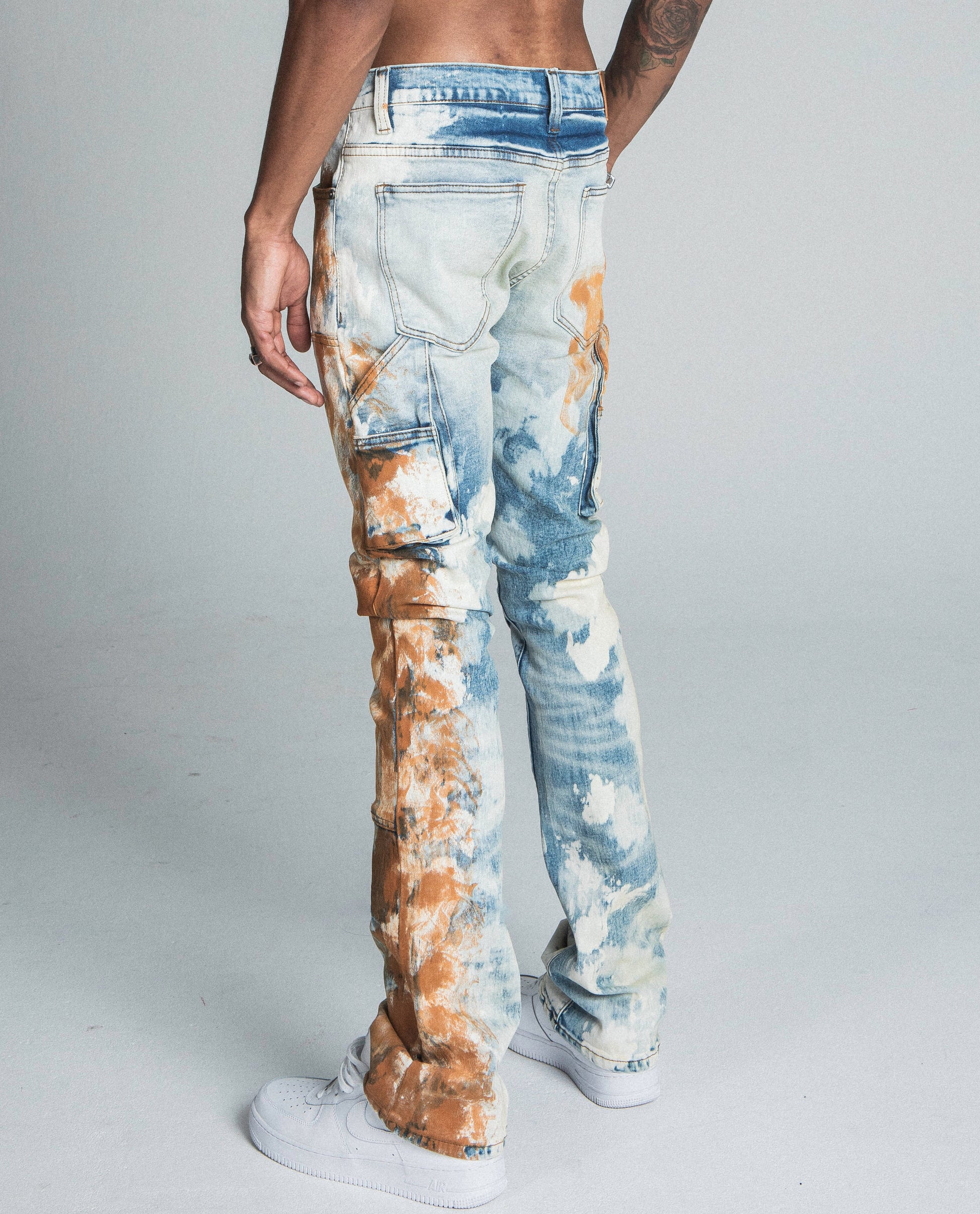 Model wearing AJ19SK OIL PAINT STACKED JEANS with traditional wash and oil design, mid-rise waist, cargo pocket, and stretchy fabric.