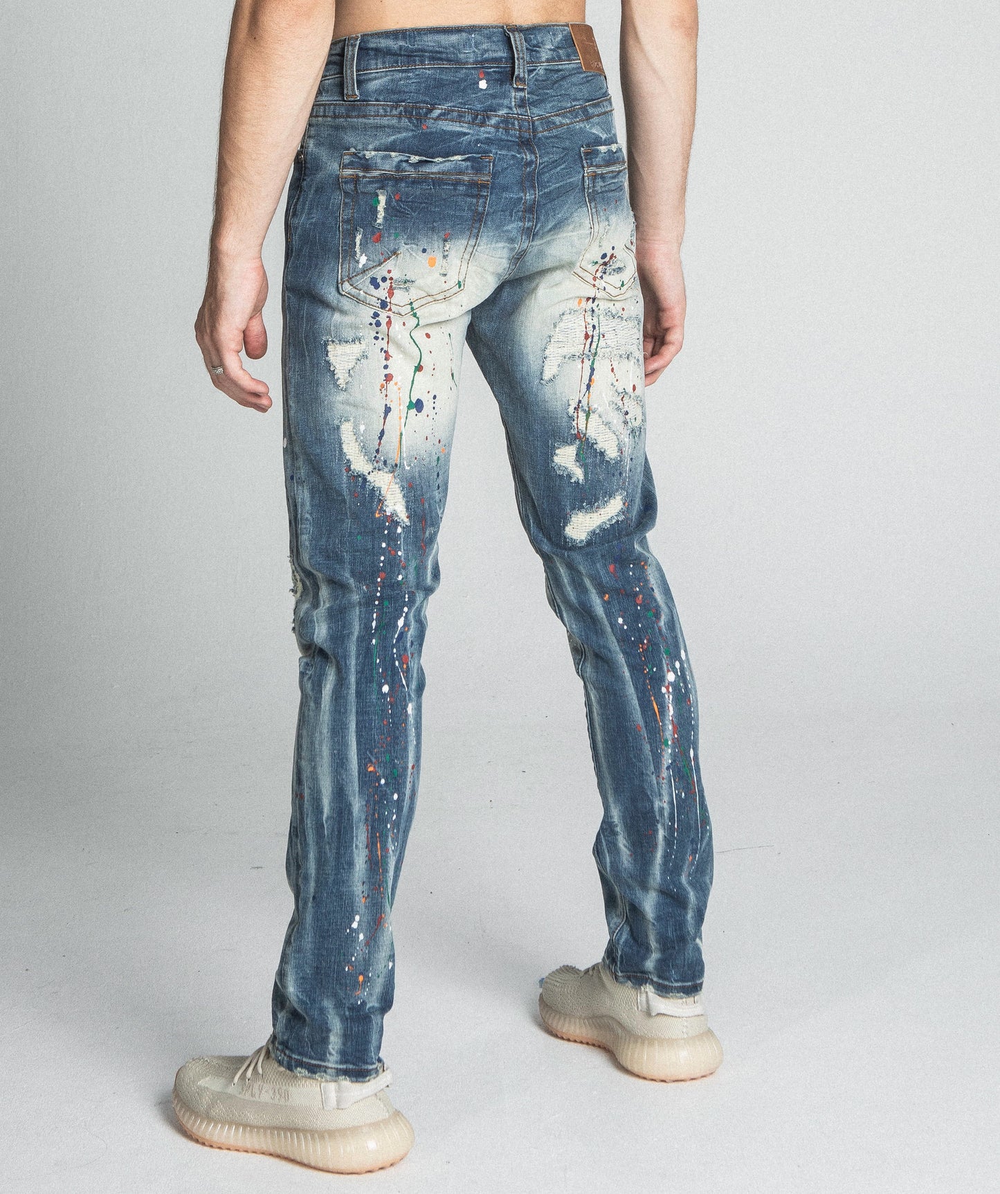 Rear view of AJ738SL-1 SPLASH PAINT VINTAGE SLIM JEANS showcasing ripped detailing and paint pattern, perfect for a trendy look.