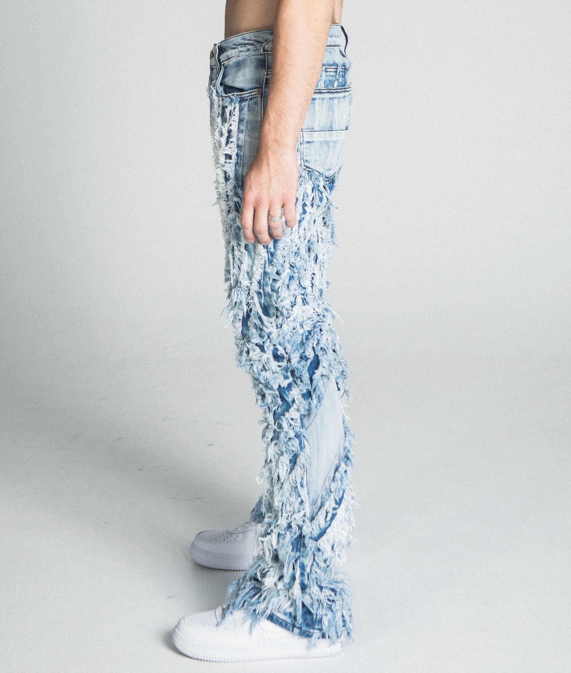 Side view of AJ18SK EXTREME FRAYED STACKED JEANS showcasing frayed design, mid-rise waist, and traditional wash.