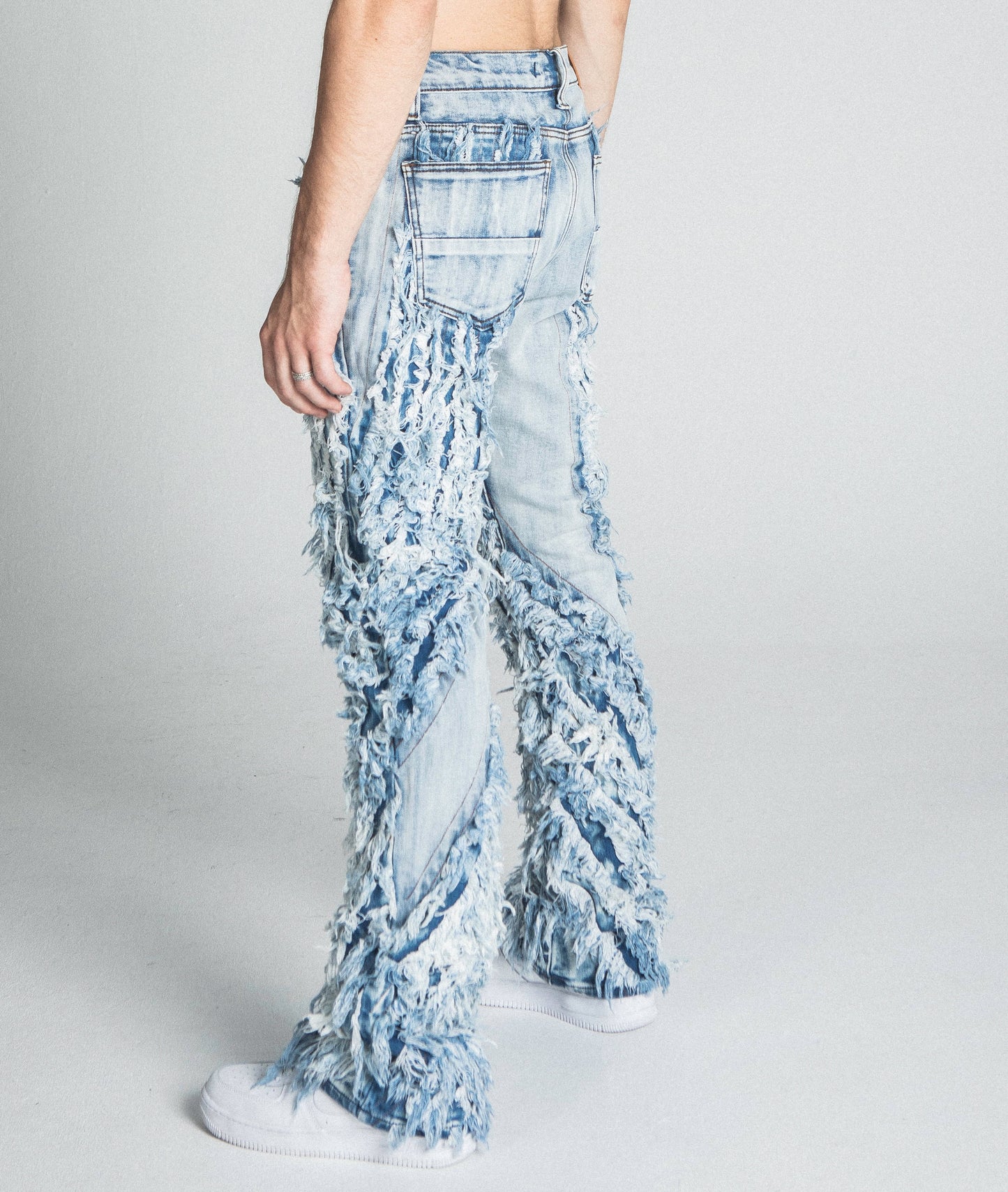 AJ18SK EXTREME FRAYED STACKED JEANS in traditional wash with mid-rise waist and extreme frayed design shown from back view.