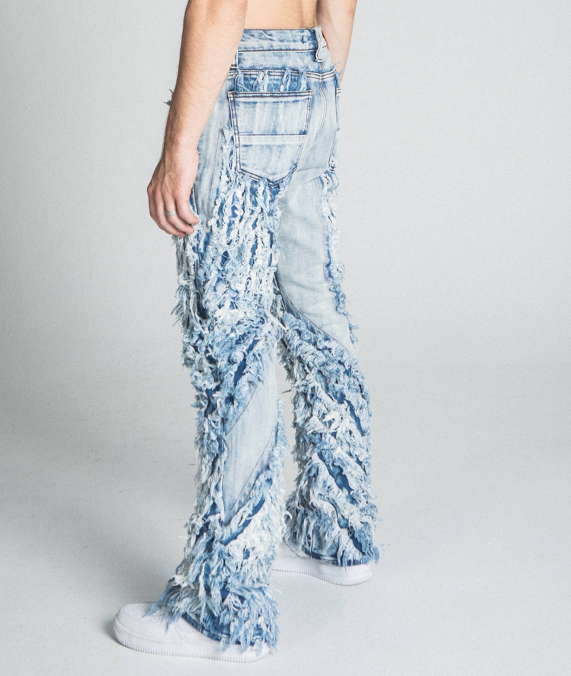 AJ18SK EXTREME FRAYED STACKED JEANS in traditional wash with mid-rise waist and extreme frayed design shown from back view.