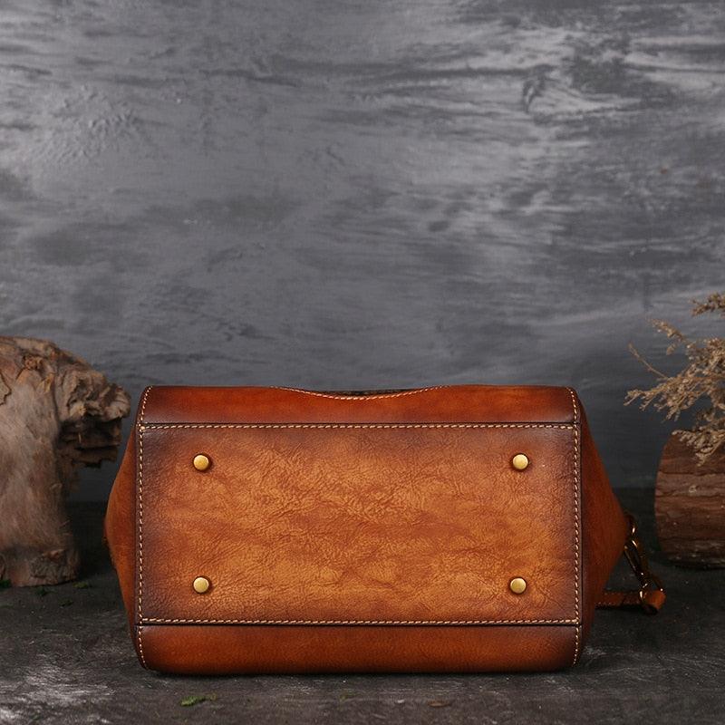 Bottom view of Mandala Embossed Leather Shoulder Bag showing its durable leather base and sturdy metal feet against a rustic background.