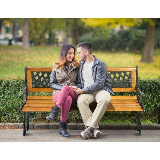 Couple sitting on an Outdoor Cast Iron Patio Bench in a park setting during fall