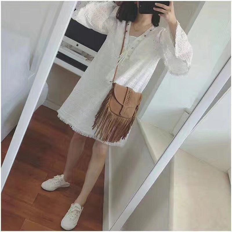 Woman wearing Dakota Tasseled Boho Leather Bag - Trendy Large Tassel Shoulder Bag with white dress and sneakers.