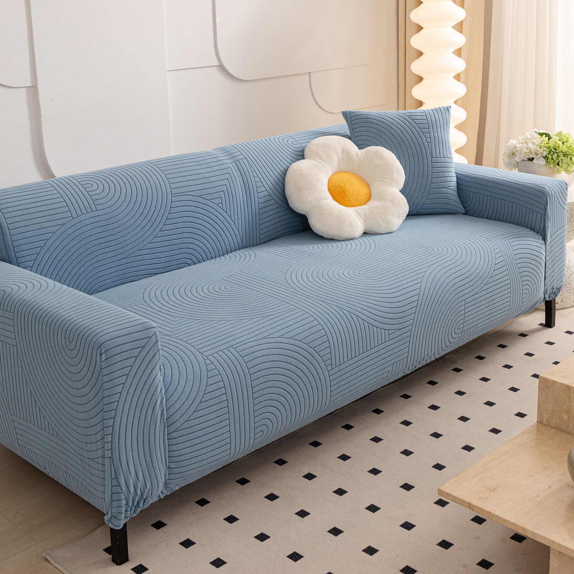 Blue sofa with geometric wave pattern covered by Fleece Stretch Sofa Slipcover Washable Soft Spandex Couch Cover Furniture Protector.