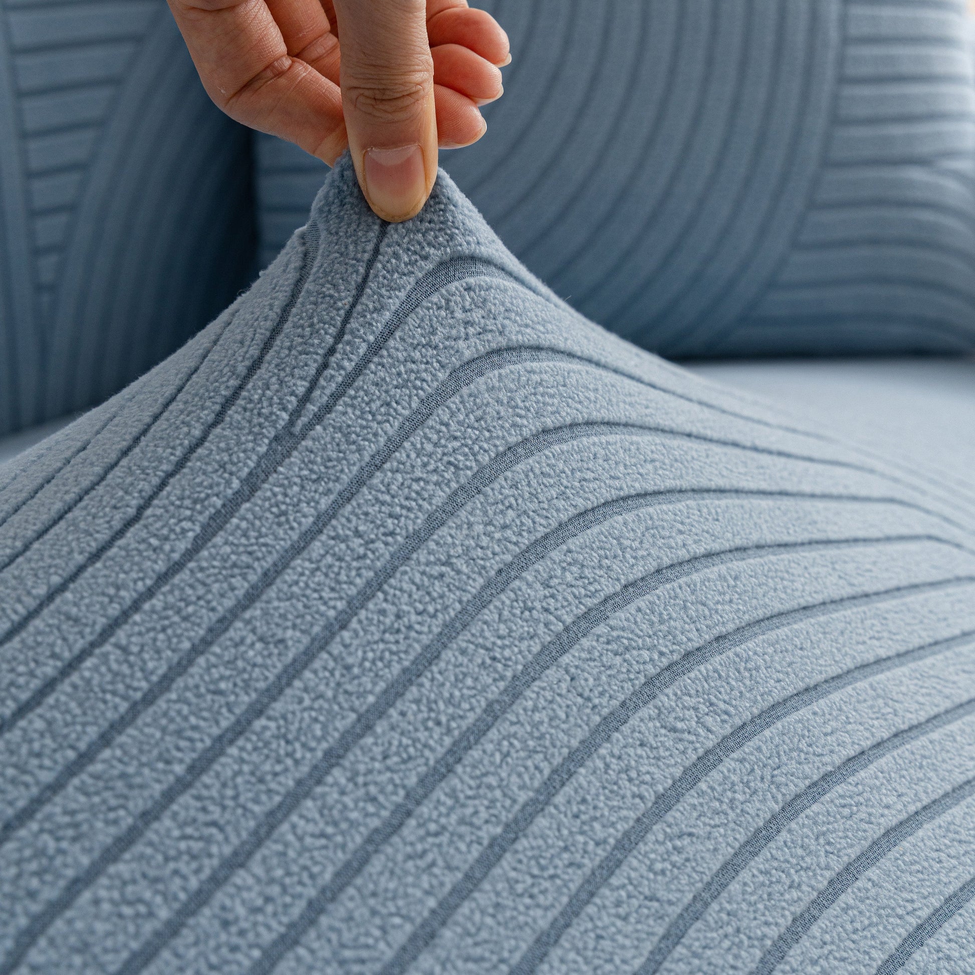 Close-up of fleece stretch sofa slipcover with modern geometric wave pattern, highlighting soft spandex texture and snug fit for furniture protection.