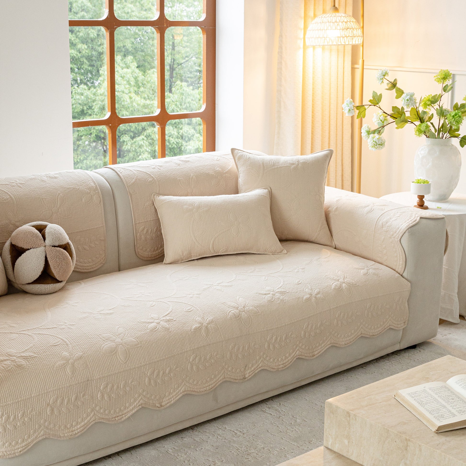 Floral Cotton Quilted Sofa Cover, Non-Slip Couch Protector with Scalloped Edges on beige sofa in elegant room setting.