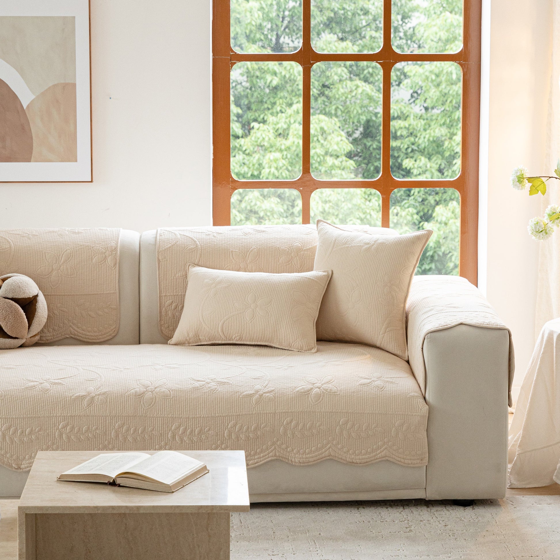 Floral Cotton Quilted Sofa Cover, Non-Slip Couch Protector with Scalloped Edges on beige couch in bright living room.