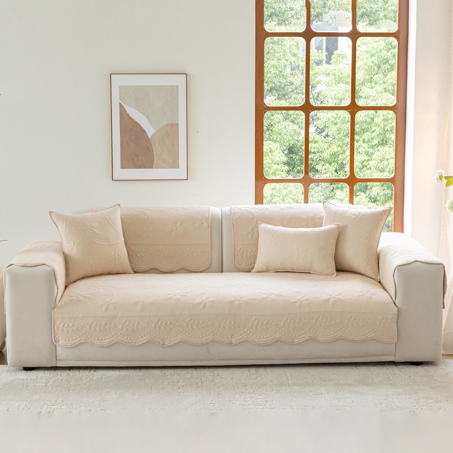 Floral Cotton Quilted Sofa Cover, Non-Slip Couch Protector with Scalloped Edges on a beige couch in a bright living room