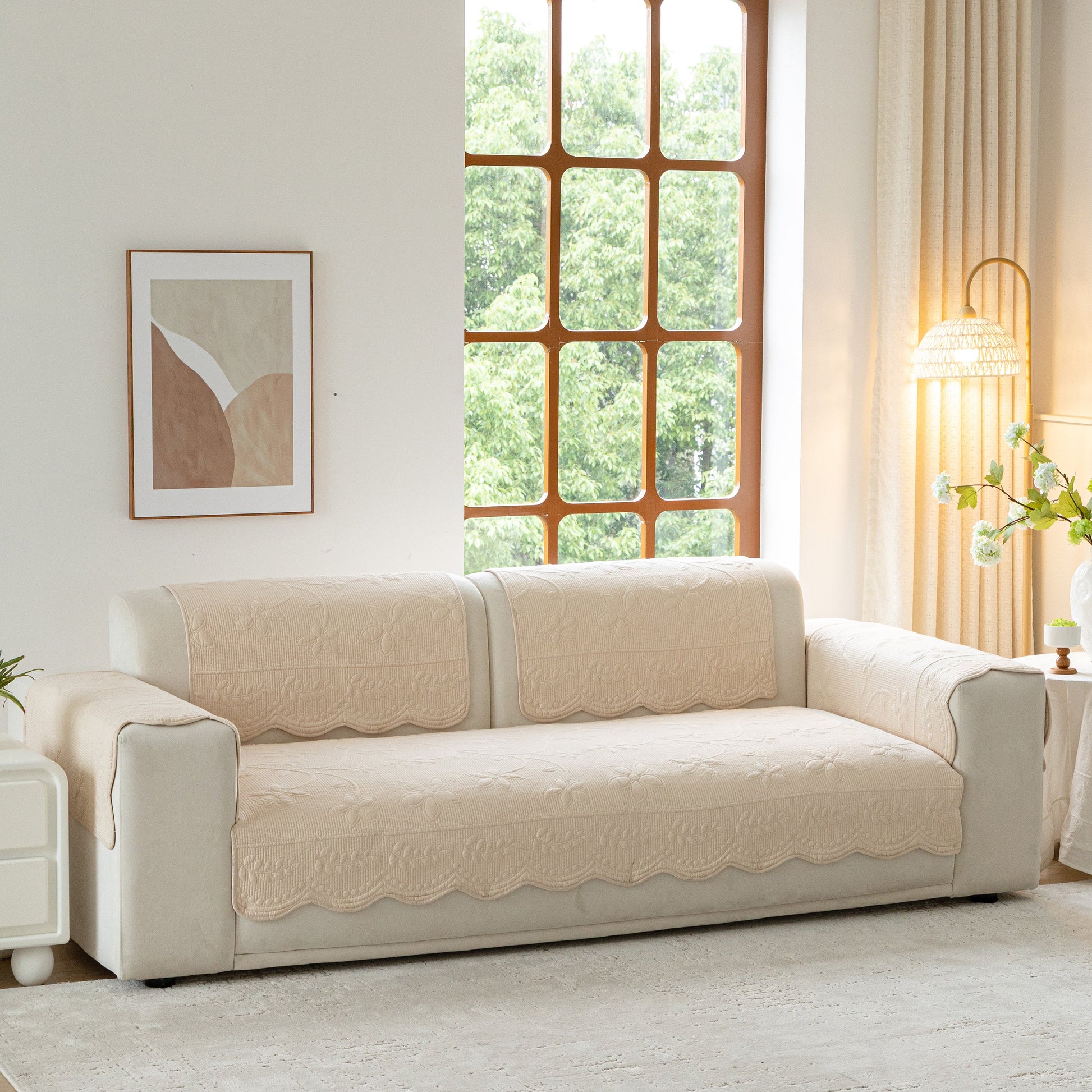 Floral Cotton Quilted Sofa Cover, Non-Slip Couch Protector with Scalloped Edges on a beige couch in a living room.