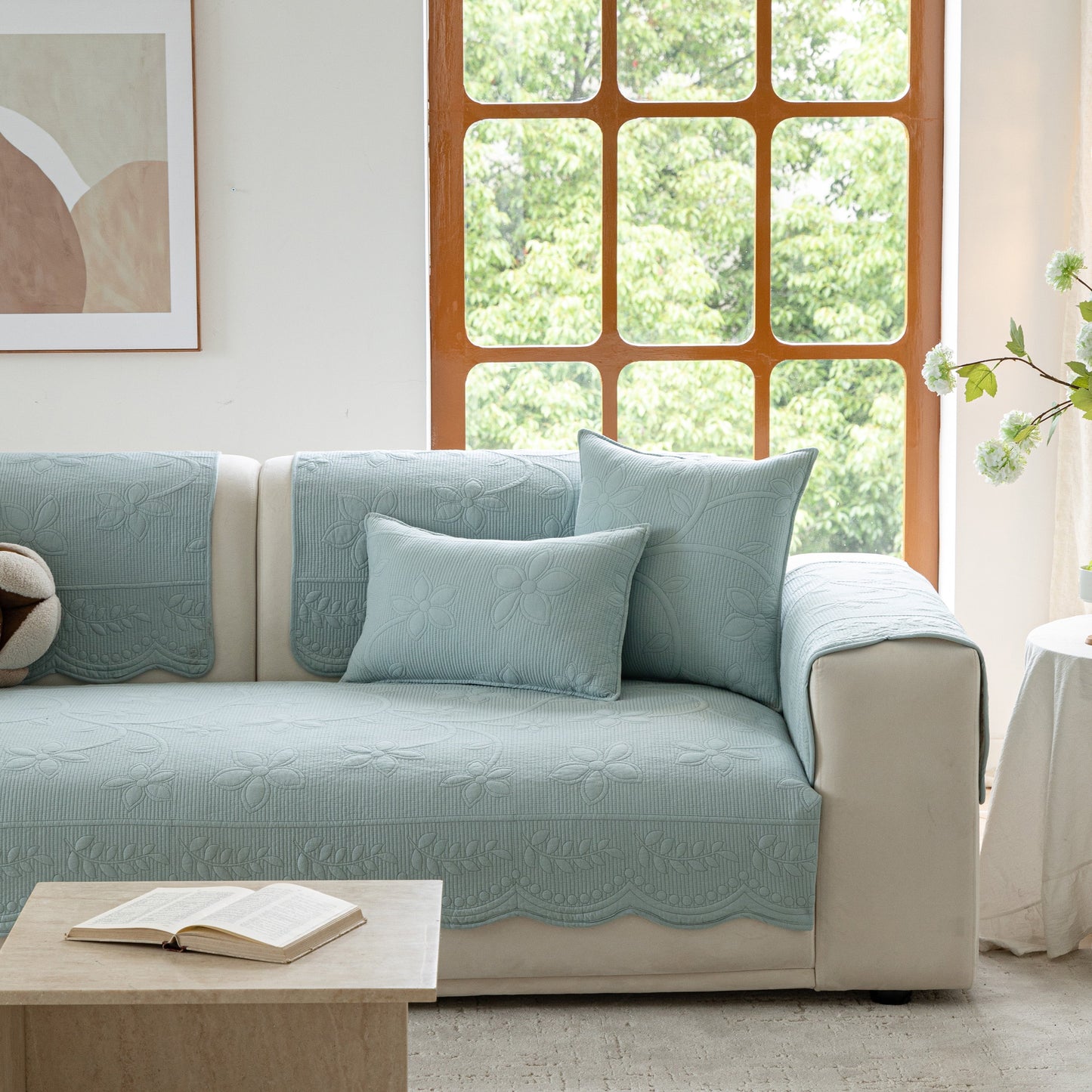Floral Cotton Quilted Sofa Cover, Non-Slip Couch Protector with Scalloped Edges on a white sofa in a bright living room.