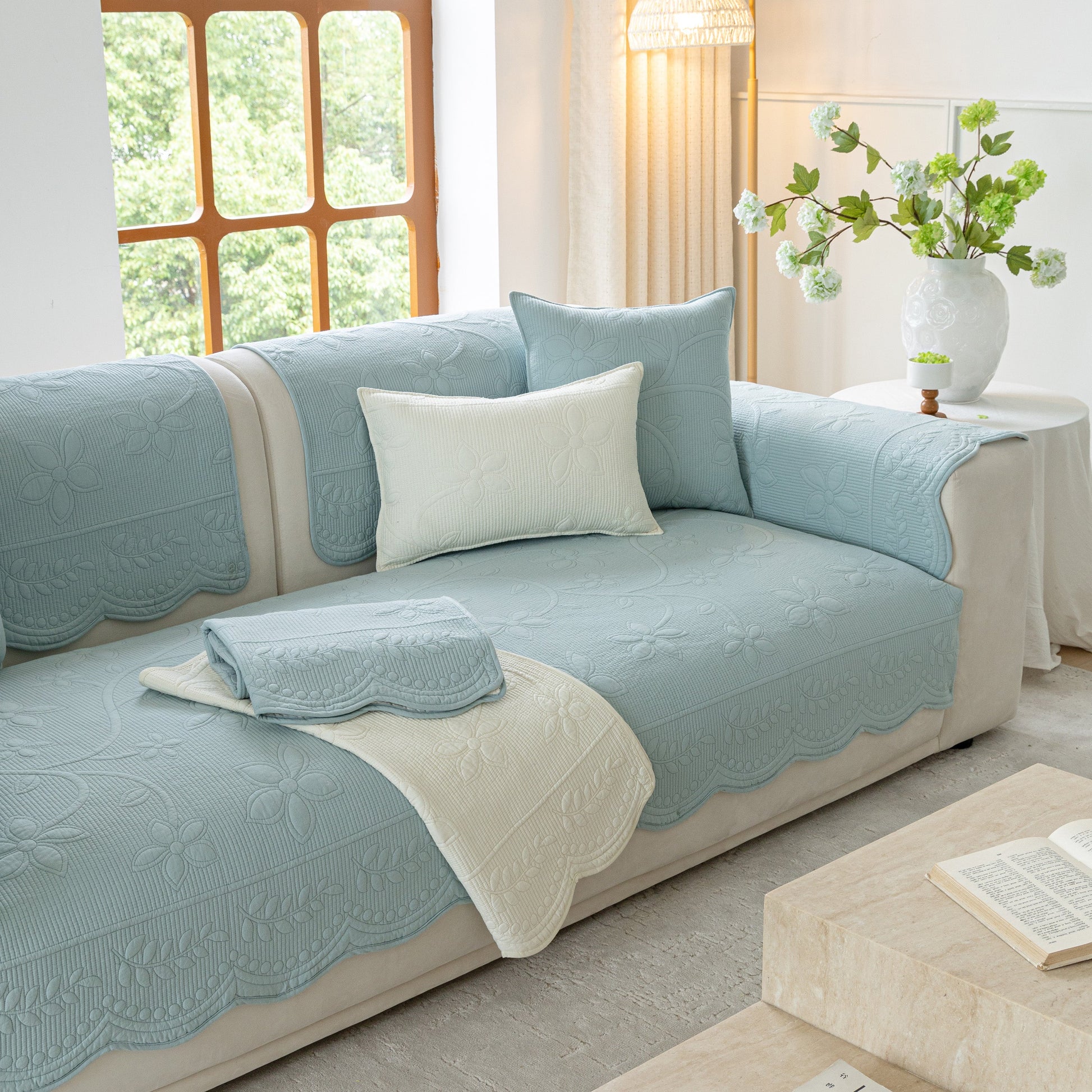 Floral Cotton Quilted Sofa Cover, Non-Slip Couch Protector with Scalloped Edges draped over a sofa in a chic living room.
