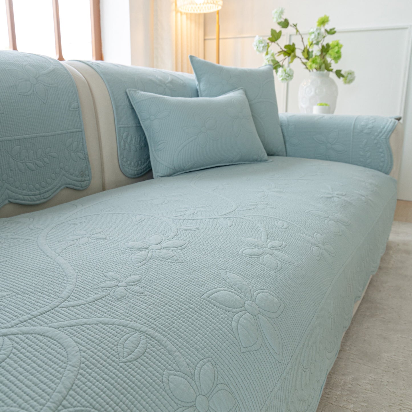 Floral Cotton Quilted Sofa Cover, Non-Slip Couch Protector with Scalloped Edges on a sofa in a living room.