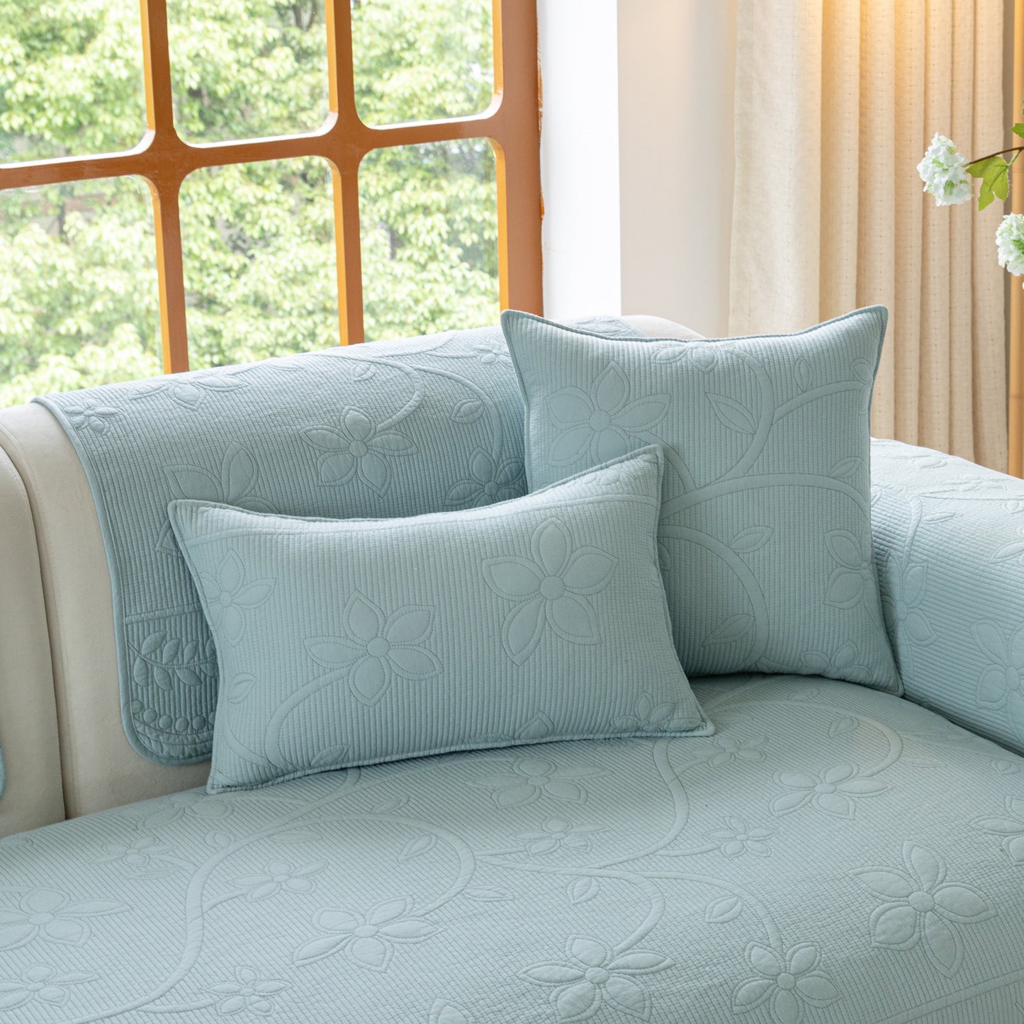 Floral Cotton Quilted Sofa Cover, Non-Slip Couch Protector with Scalloped Edges displayed on a sofa in a cozy living room.