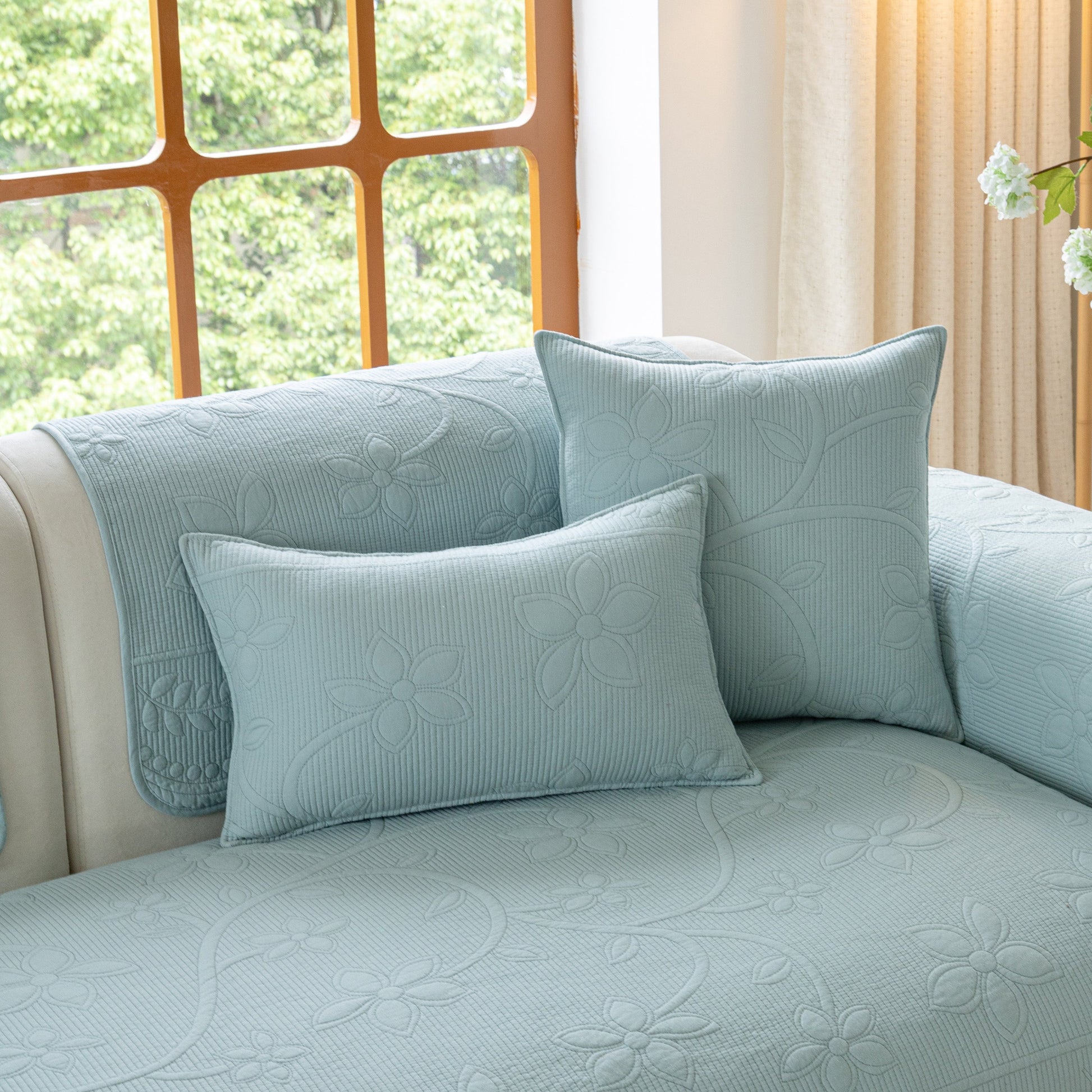 Floral Cotton Quilted Sofa Cover, Non-Slip Couch Protector with Scalloped Edges displayed on a sofa in a cozy living room.