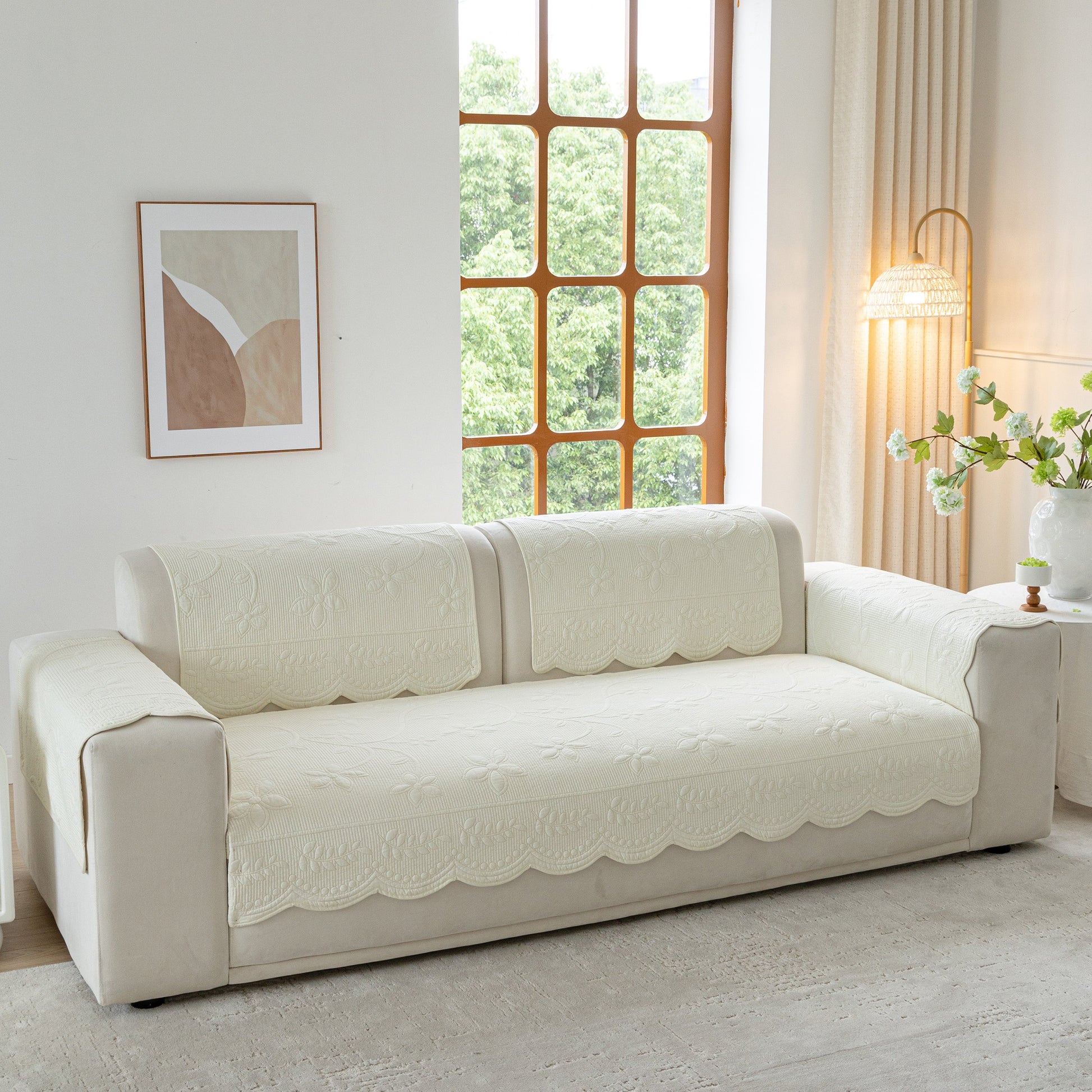 Floral Cotton Quilted Sofa Cover, Non-Slip Couch Protector with Scalloped Edges on beige sofa in bright living room.