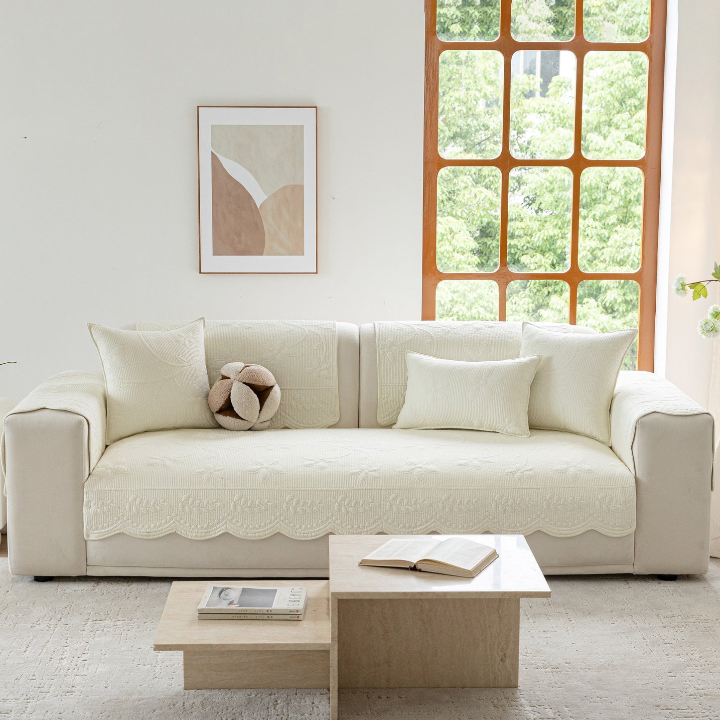 Floral Cotton Quilted Sofa Cover, Non-Slip Couch Protector with Scalloped Edges on a beige sofa in a bright living room.