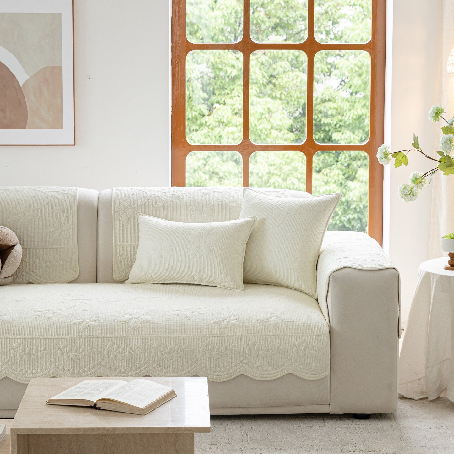 Floral Cotton Quilted Sofa Cover, Non-Slip Couch Protector with Scalloped Edges on a white sofa in a bright living room.