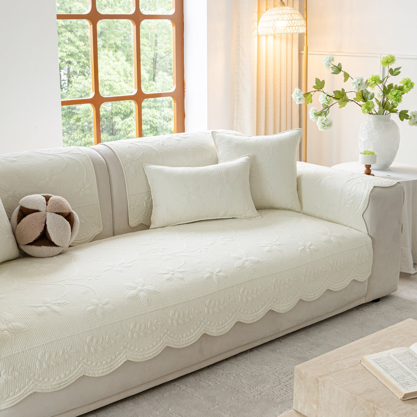 Floral Cotton Quilted Sofa Cover, Non-Slip Couch Protector with Scalloped Edges on white couch in living room.